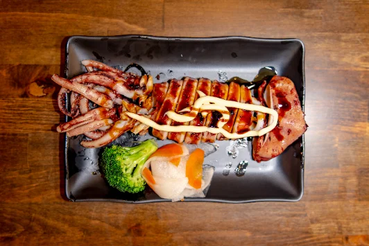 A grilled small plate with broccoli and a pickled garnish