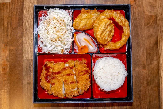 A bento box with rice, a breaded cutlet, salad and sides